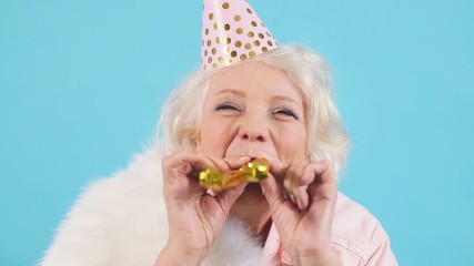 Cheerful pleasant pretty old lady holding party horns and looking at camera, entertainment.