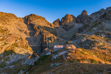 Amazing landscape of The Scary lake during warm summer sunset with small stone shelter, Rila mountain national park, Bulgaria