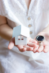 Little girl kid holding little house and key in hands