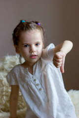 Cute little girl holds a thumb down