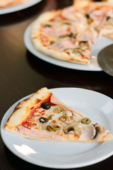 Mushroom pizza slice on white ceramic plate over the table.