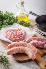 uncooked sausage and ham on white wooden board