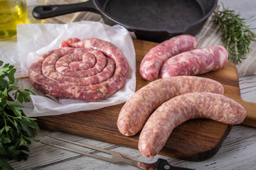 uncooked sausage and ham on white wooden board