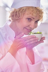 Closeup of confident chef smelling fresh mint leaves in kitchen at restaurant
