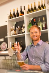 Young waiter filling glass from beer tap at restaurant