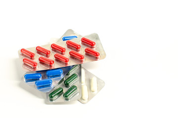 Bright red, white, green and blue pharmaceuticals pills in a silver blister packaging over a white background. Health care concept. Isolated. With place for text.