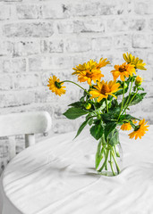 Bouquet yellow autumn flowers on a table in a cozy light kitchen. Copy space, flat lay