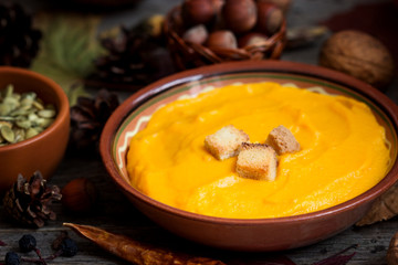 Pumpkin soup with crackers, nuts, seeds on an autumn table.