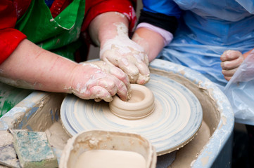 An experienced master in the production of jugs teaches a student to make a jug form on a machine, close-up