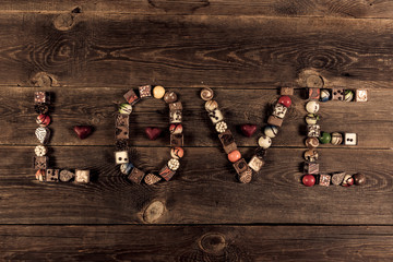 Obraz na płótnie Canvas LOVE word arranged with pralines on the wooden plank background