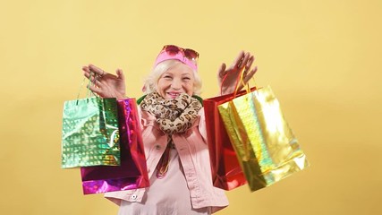 Cheerful cool granny with raised arms holding many shopping bags. Happines, emotion and feeling