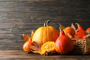 Straw basket, pumpkins, leaves and cinnamon on wooden background, copy space