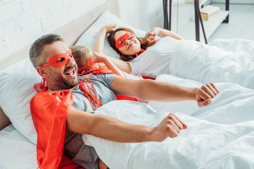 happy family in superheroes costumes stretching while awakening in morning