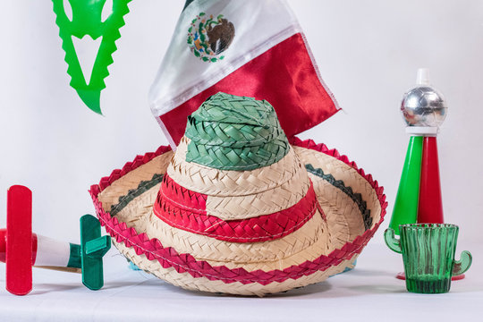 Matraca, hat, mexican flag, cornet and glass of tequila on white background