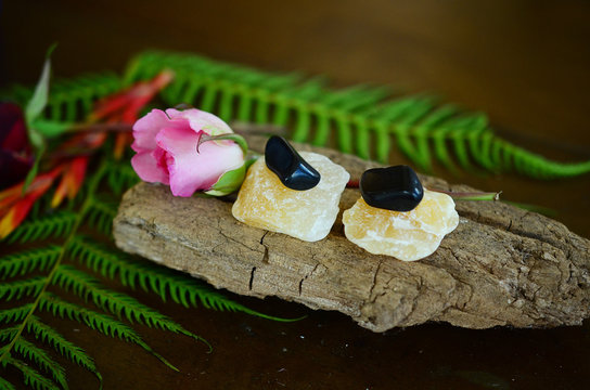 Tumbled Apache Tear and Rough Orange Calcite Duo! Black and Orange, harvest crystals. Witches fall time theme healing crystal bundle. Beautiful, colorful crystal display on wooden table. Natural light
