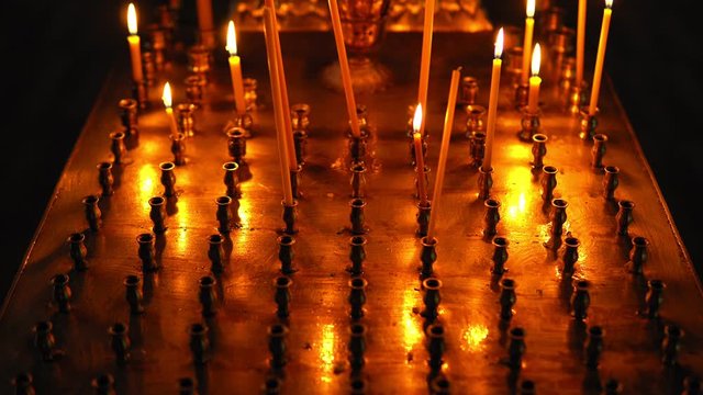 Large Golden table candlestick with burning candles in the Orthodox Church. Camera rises from bottom up, focus is smoothly focused on candles close-up.