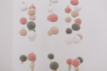 Details of newborn baby room. Toys above the baby crib. Hanging carousel of soft colorful balls for the child.