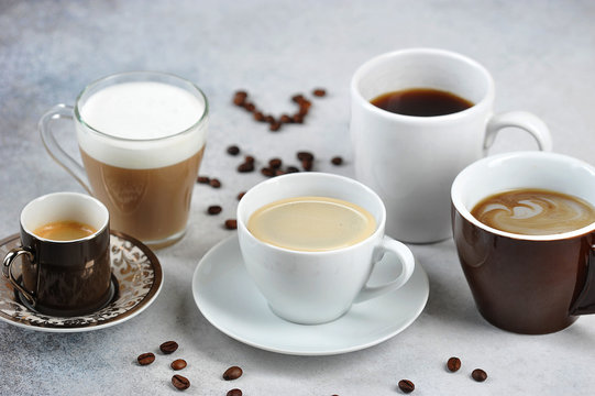 Set of different types of coffee in different cups. Espresso, cappuccino, Americano, latte are presented. Coffee beans on the surface of a light table.