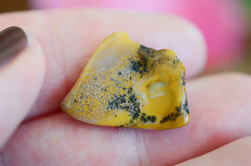 Small delicate tumbled ocean jasper in woman's hand. Macro photography of healing crystal textures, intricate details of Ocean Jasper stone from Madagascar. Rare healing crystal. Stunning details