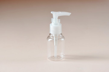Empty transparent plastic bottle on a light background. Bottle for storing and transporting cosmetics.