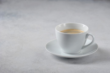 Coffee in a white cup on a light background. Free space for text.