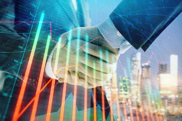 Double exposure of financial chart on cityscape background with two businessmen handshake. Concept of financial analysis and investment opportunities