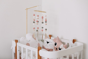 Beautiful interior of baby room. White crib with pillows and pink blanket in baby room.  pink bedding on bed against white wall