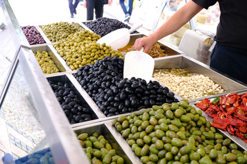 Various marinated olives for sale in a market window.