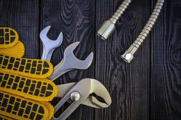Fototapeta premium Plumbing tools and gloves for connecting water hoses on a black wooden background.