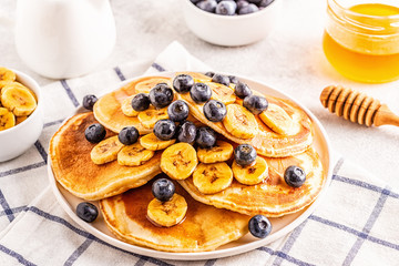 Pancakes with banana,  blueberries on white plate.