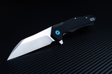 Folding pocket knife diagonally. Black background. Shiny blade.