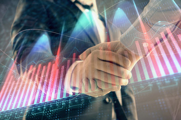 Multi exposure of forex graph on abstract background with two businessmen handshake. Concept of success on stock market