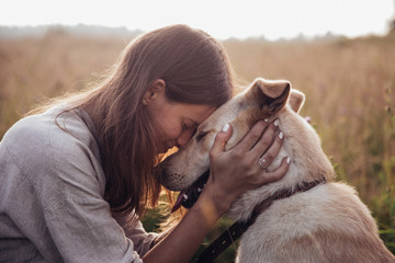 Girl and her friend dog on the straw field background. Beautiful young woman relaxed and carefree enjoying a summer sunset with her lovely dog - Powered by Adobe