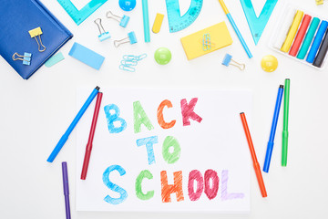 Top view of paper with back to school lettering near colorful felt-tip pens and stationery isolated...