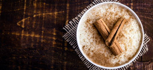 Creamy rice pudding sprinkled with cinnamon, typical Brazilian dessert. Tasty dessert on rustic wood background.