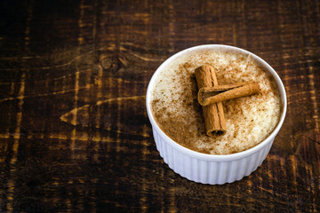 Typical sweet of Brazil in June and July parties. Sweet rice porridge with cinnamon in a bowl on a background.