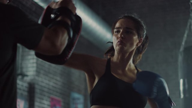 Fit Athletic Woman Kickboxer Punches the Punching Pads During a Workout in Gym