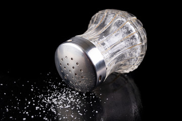 Glass salt shaker with metal cap on the kitchen table. Kitchen accessories for seasoning dishes.