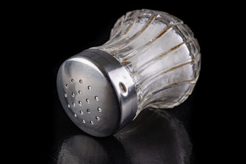 Glass salt shaker with metal cap on the kitchen table. Kitchen accessories for seasoning dishes.