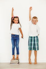 Obraz premium Little boy and girl measuring their height isolated on white background