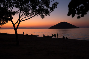 Fototapeta na wymiar Lake Malawi at Monkey Bay, People gathering togehter at the Beach, washing dishes, talking, red sunset, South-East-Africa