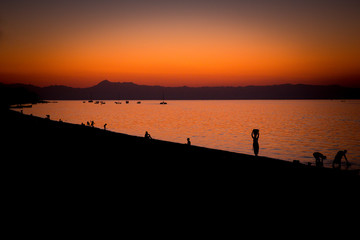 Fototapeta premium Lake Malawi at Monkey Bay, People gathering togehter at the Beach, washing dishes, talking, red sunset, South-East-Africa