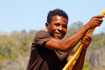 Young Malagasy rafter man rowing traditional canoe on river, Madagascar