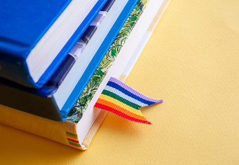 a stack of three books with rainbow ribbon bookmarks is on the table. Concept back to school,...