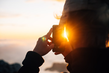 person takes picture of the sunset with sunflair