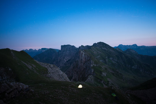 illuminated tent on a mountain ridge