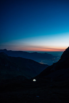 illuminated tent in the mountains with sunrise in the background