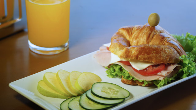 crossaint with tomato lettuce accompanied by cucumber and apple