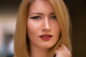 Naklejka premium blonde girl with wide make up arrows on the eyes posing in the street