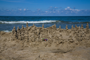 Fototapeta na wymiar Sand castle on the blue sea. Beach games. Holidays at sea with children..